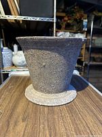 Front view of the cast-iron mortar showing overall shape, texture, and the chip on the top rim.