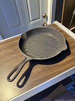 Top view of the cast iron grill pan showing handle and ridged grilling surface.