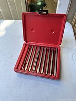 Red plastic case containing 8 steel parallel bars arranged side by side.