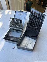 Two metal cases containing USA made twist drill bit sets with multiple sizes and some extra bits in smaller set.