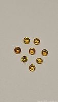 Seven natural round cut yellow sapphires laid on neutral background showing size and color variety