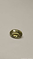 Oval cut lemon citrine gemstone with high clarity and yellow hue on neutral background.