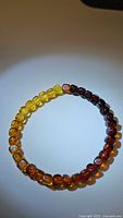 Round polished beads of natural Baltic amber arranged in a gradient from yellow to dark brown forming a stretchy bracelet.