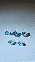 Photo showing five oval cut natural Cambodian blue zircon gemstones in seafoam blue color with good clarity under neutral light.