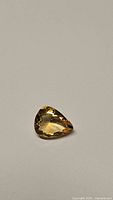 Photo of the natural golden citrine pear cut gemstone showing its color, shape, and faceting.