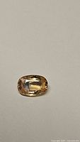 Oval cushion-cut sapphire resting on neutral background, top view.