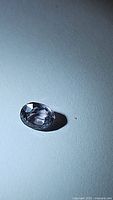 Photo of an oval cut purple spinel gemstone on a plain background showing the gemstone's clarity and cut.