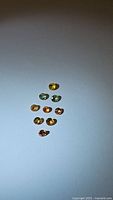 Nine round faceted natural rainbow sapphires of various colors on white background, displaying different hues under light.