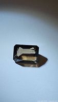 Natural emerald cut smokey quartz gemstone shown on white background, highlighting the rectangular shape and the brown gray transparent color.