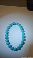 Front view of the stretchy bracelet laid flat on a white surface showing round robin's egg blue turquoise beads strung evenly.