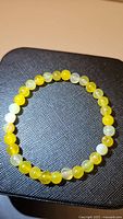 Top view of natural yellow agate bracelet on dark textured background showing the full circle of 6mm round yellow agate beads.