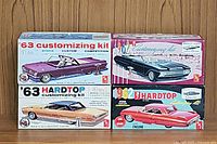 Four vintage AMT plastic model car kit boxes showing 1963 Bonneville, 1963 Ford Fairlane, 1962 Lincoln Continental, and 1962 Buick convertible models with colorful box art and branding details.