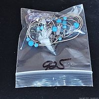 Zip-top bag containing loose jewelry components: multicolored beads, beaded chain, and three pendants