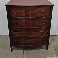 Front view of antique mahogany highboy chest of drawers showing 4 drawers with brass pull handles and curved fronts.