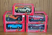 Five boxed Bburago 1/24 scale diecast cars stacked showing front of the boxes.