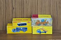 Original yellow Dinky Toys boxes for various vehicles including BOAC bus #283, Berliet tipper truck, Albion cement mixer showing colorful vehicle images and logos