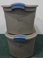 Front view of two stacked beige plastic storage containers with blue latches and markings '010' and '011'.