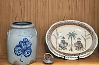 Photo of lot showing stoneware crock, ceramic platter, and mini teapot against wood panel background.
