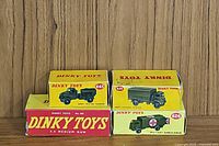 Front view of four original yellow and red boxed Dinky Toys military vehicles, showing model numbers and matching vehicles