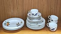 Full set of Royal Worcester Evesham china stacked showing plates, bowls, cups, and saucers with fruit pattern and gold rim detail.
