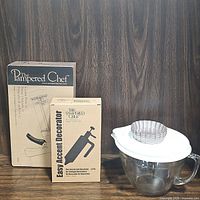 Photo shows the full lot with Pampered Chef cookie press box, Easy Accent decorator box, 8-cup glass mixing bowl with white lid, and six mini tart tins on top of the lid.