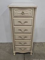 Front view of the white French Provincial style lingerie chest showing six closed drawers and ornate drawer pulls.