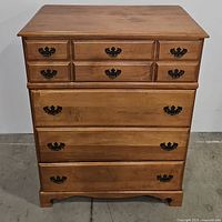 Front view of maple chest showing four drawers with brass hardware.
