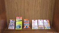 Six Matchbox cars in original packaging displayed on a wooden surface and background, showing their blister packs and card backing.