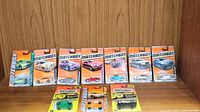 Displayed 11 Matchbox diecast cars in sealed packaging on wooden shelf, various models and colors visible.