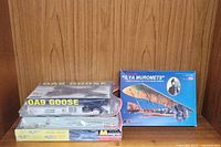 Three sealed aircraft plastic model kits stacked, showing brands and scale information on boxes.
