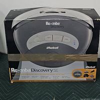 Front view of original box showing iRobot Roomba Discovery SE unit with handle and control buttons on top panel.
