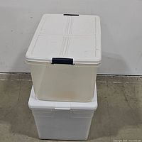 Two stacked plastic storage containers: top is clear with blue clips, bottom is white opaque with white lid.
