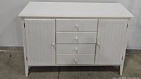 Front view of the white sideboard showing 3 drawers and 2 cabinet doors with paneled design.