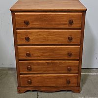 Front view of the wooden chest showing 5 drawers with wood knobs, in a maple style finish.