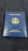 Closed blue US Mint presentation box stamped “AMERICAN BUFFALO” and “ONE OUNCE GOLD PROOF COIN”