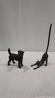 Full view of both cast iron animal figures: Fox Terrier dog statue and stretching cat paper towel holder.