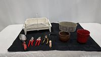 Collection of gardening tools and pots arranged on black cloth showing tools and containers.