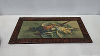 Full view of the vintage pheasant painting on canvas inside a wooden frame placed on a flat surface.