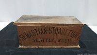 Front view of a rectangular wooden box with 'Sebastian Stuart Fish Co. Seattle Wash' stenciled in black on the front side.