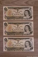 Front side of 3 consecutive 1973 Canadian $1 banknotes featuring Queen Elizabeth II.