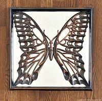 Front view of the copper butterfly mirror showing the detailed cut-out wings and mirror surface inside the copper frame.