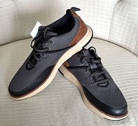 Side view of Cole Haan men's Zerogrand sneakers showing grey mesh upper, brown suede heel, white midsole, and black outsole.