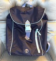 Front view of black backpack with light purple strap and reflective piping.