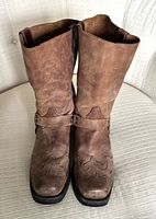 Front view of brown leather cowboy boots showing wear and stitched decorative designs on toes.