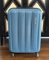 Front view of Probeetle by Eminent hard-shell suitcase showing vertical ridges and logo plaque.