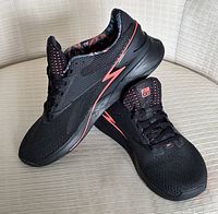 Pair of black Reebok Nano X3 sneakers showing side angle and pink lightning bolt detail.