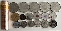 Stacked rolls of coins with several laid out, showing variety of Canadian commemorative dollar coins, quarters with colored details, pennies and nickels.