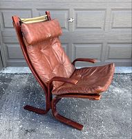 Side angle view of the vintage Westnova leather Siesta chair showing leather wear, wooden frame, and headrest cushion.