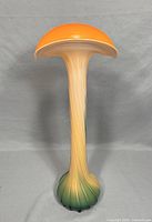 Full view of the glass calla lily vase showing its tall stem and flared orange top with smooth white edge.