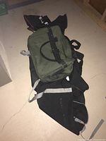 Black fabric Kneissl ski bag laying on floor with a smaller green bag on top